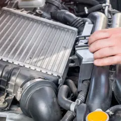 Mano ajustando un intercooler, componente clave para enfriar el aire del motor.