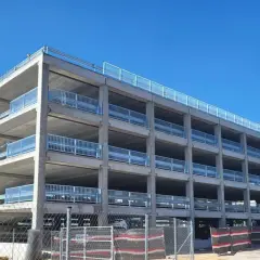 Estructura de hormigón de un parking disuasorio en Barcelona, con varias plantas y barandillas metálicas, bajo un cielo azul.