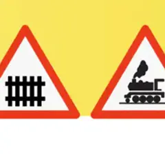 Dos señales de advertencia triangulares con borde rojo sobre fondo amarillo. Una muestra vías de tren, la otra una locomotora. Indican un paso a nivel con barreras.