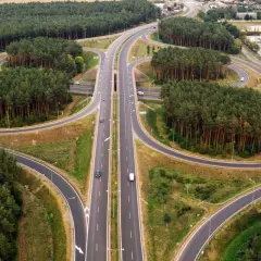 Un cruce de autopistas con un carril trenzado serpentea entre bosques de pinos.