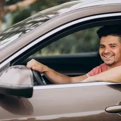 Hombre sonriente al volante, disfrutando de un viaje. La pregunta sobre hasta qué edad se puede conducir en España es relevante para muchos.