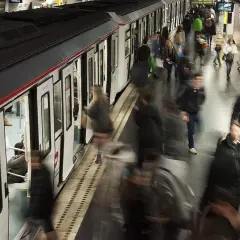 Gente abordando un tren en una estación de metro, con el movimiento borroso sugiriendo la actividad constante de las obras del metro de Barcelona.