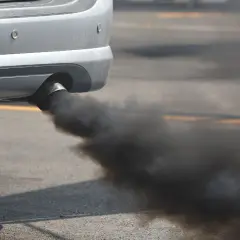 El tubo de escape de un coche emite humo negro denso, sugiriendo un fuerte olor a quemado de coche.