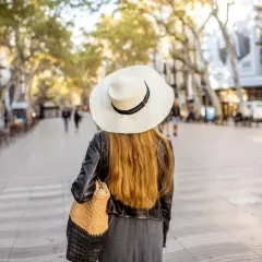 Mujer con sombrero pasea por Las Ramblas de Barcelona, un mapa visual de la ciudad.