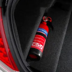 Extintor rojo en el maletero de un coche, listo para usar. Es obligatorio llevar extintor en el coche para tu seguridad.