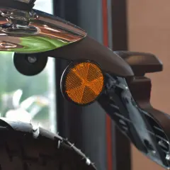 Detalle de una moto con un catadióptrico naranja que refleja la luz, aumentando la seguridad.