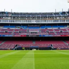 El estadio Spotify Camp Nou en obras, con grúas visibles. Las gradas rojas y azules esperan a los aficionados tras la renovación, cerca de la estación de metro.