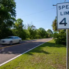 Señal de límite de velocidad de 40 en una carretera convencional. Un coche blanco pasa a gran velocidad.