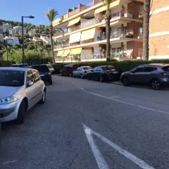 Coches aparcados en una calle con edificios residenciales al fondo. Hay varias opciones de parking gratuit Sitges.