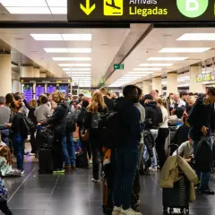Gente esperando en un aeropuerto, buscando información sobre cómo usar el metro de Barcelona.