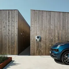 Coche azul conectado a uno de los puntos de recarga en una pared de madera.