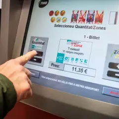 Dedo tocando pantalla para comprar billete T-casual de zona 1 en Barcelona.