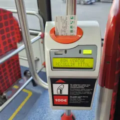 Validando billete para prendre le bus a Barcelone. Asientos rojos con patrón de cuadros en el interior del autobús.
