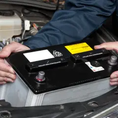 Mecánico manipulando una batería de coche para desconectar la batería coche.