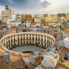 Vista aérea de la Plaza de Toros de Valencia, un edificio circular con balcones, como si se viajara en el tren de Barcelona a Valencia.