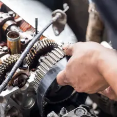 Mecánico ajustando la correa de distribución, una pieza clave para saber cada cuanto se cambia la correa de distribución y mantener el motor en óptimas condiciones.