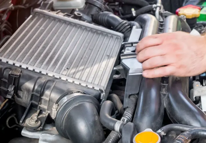 Mano ajustando un intercooler, componente clave para enfriar el aire del motor.