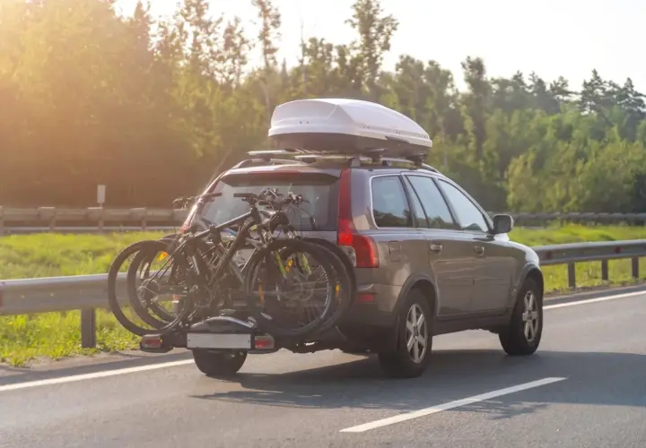 Turismo con portabicicletas y cofre de techo. La carga sobresale bastante, ideal para viajes largos.