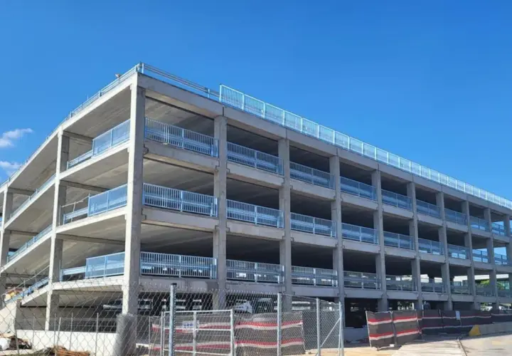 Estructura de hormigón de un parking disuasorio en Barcelona, con varias plantas y barandillas metálicas, bajo un cielo azul.