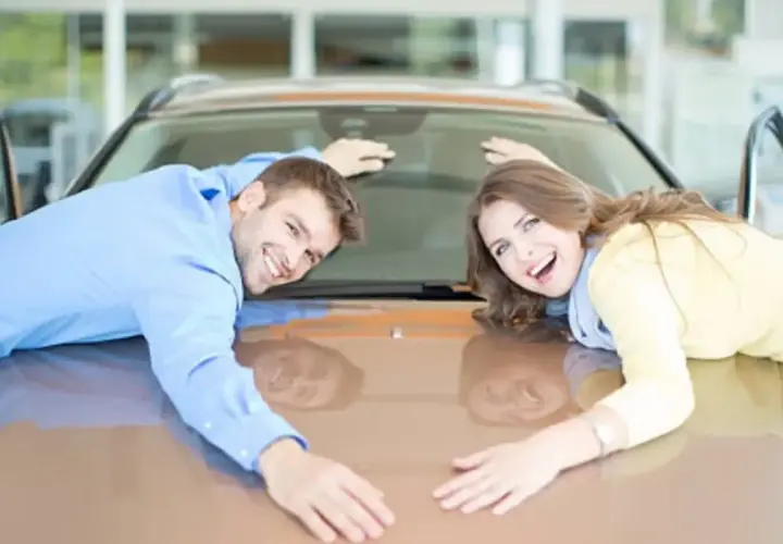Pareja feliz abraza su nuevo coche, demostrando que se puede poner un coche a nombre de dos personas.