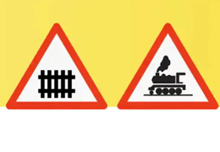 Dos señales de advertencia triangulares con borde rojo sobre fondo amarillo. Una muestra vías de tren, la otra una locomotora. Indican un paso a nivel con barreras.