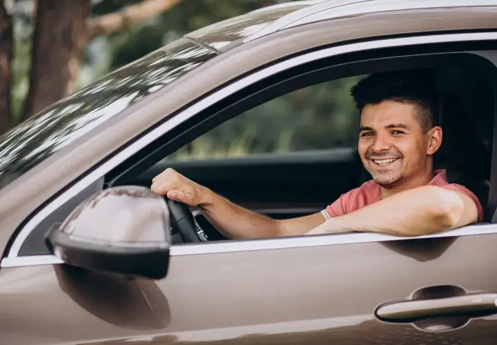 Hombre sonriente al volante, disfrutando de un viaje. La pregunta sobre hasta qué edad se puede conducir en España es relevante para muchos.