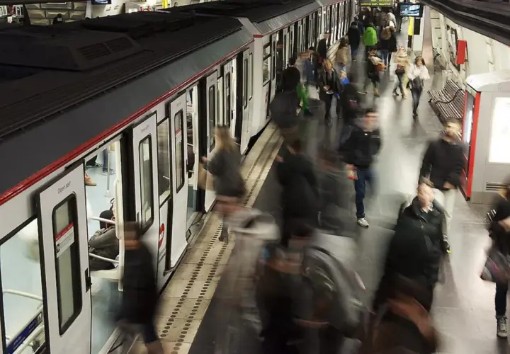 Gente abordando un tren en una estación de metro, con el movimiento borroso sugiriendo la actividad constante de las obras del metro de Barcelona.