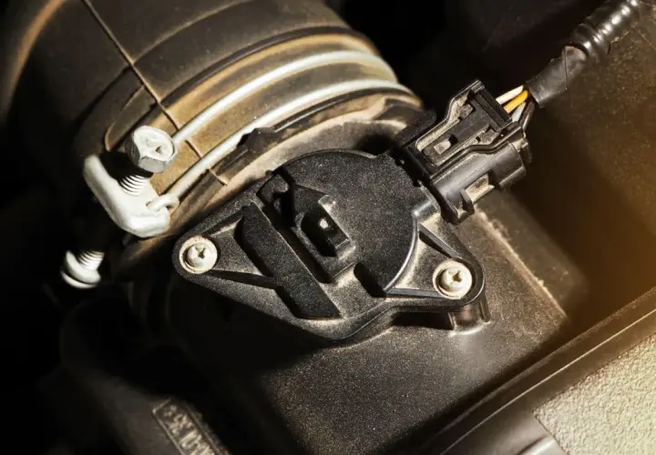 Sensor map de un coche, con un conector negro y cables amarillos y blancos.
