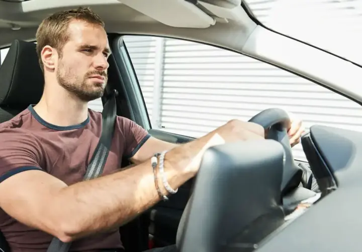 Hombre frustrado al volante, su coche no arranca.