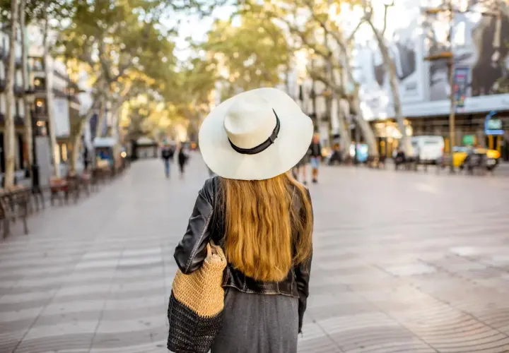 Mujer con sombrero pasea por Las Ramblas de Barcelona, un mapa visual de la ciudad.