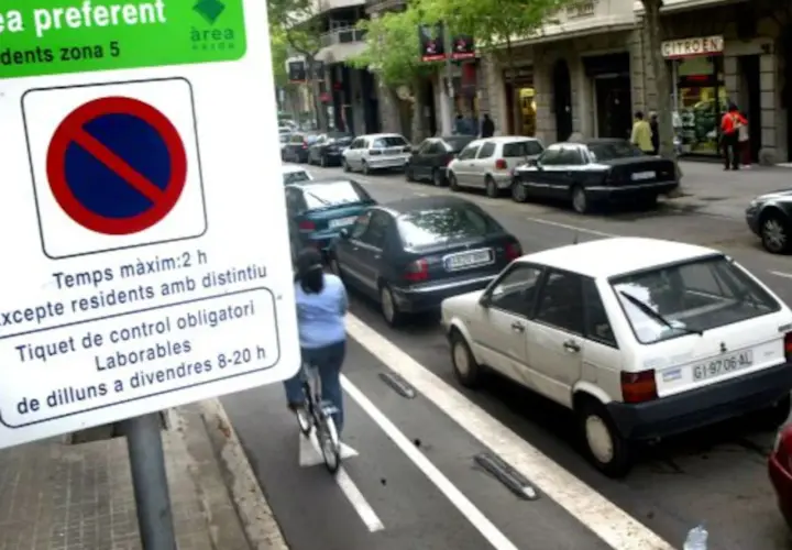 Zona verte Barcelona domingo: señal de estacionamiento, ciclista y coches aparcados en la calle.