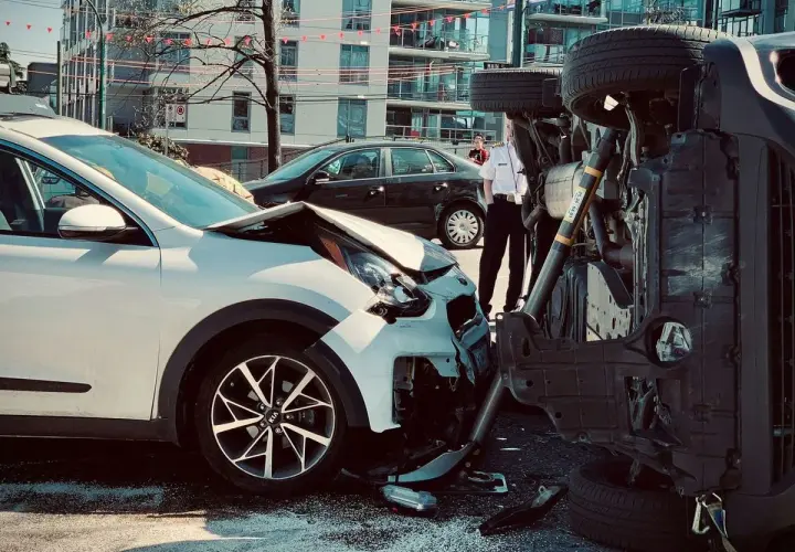 Dos coches involucrados en un accidente. Uno blanco, con el capó destrozado. El otro, volcado, muestra un siniestro total.