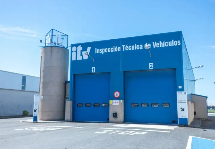 Edificio azul de ITV con dos puertas de garaje. Un coche listo para pasar la primera ITV.