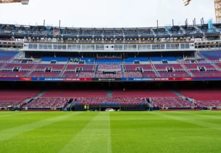 El estadio Spotify Camp Nou en obras, con grúas visibles. Las gradas rojas y azules esperan a los aficionados tras la renovación, cerca de la estación de metro.