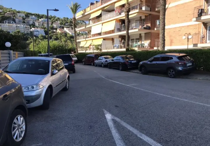 Coches aparcados en una calle con edificios residenciales al fondo. Hay varias opciones de parking gratuit Sitges.