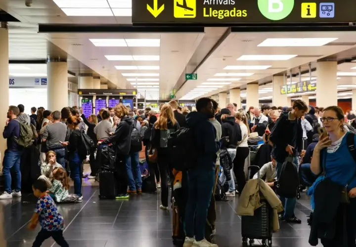 Gente esperando en un aeropuerto, buscando información sobre cómo usar el metro de Barcelona.