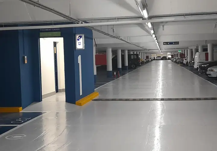 Entrada al parking Rius i Taulet. Pasillo con coches aparcados y señalización de salida.