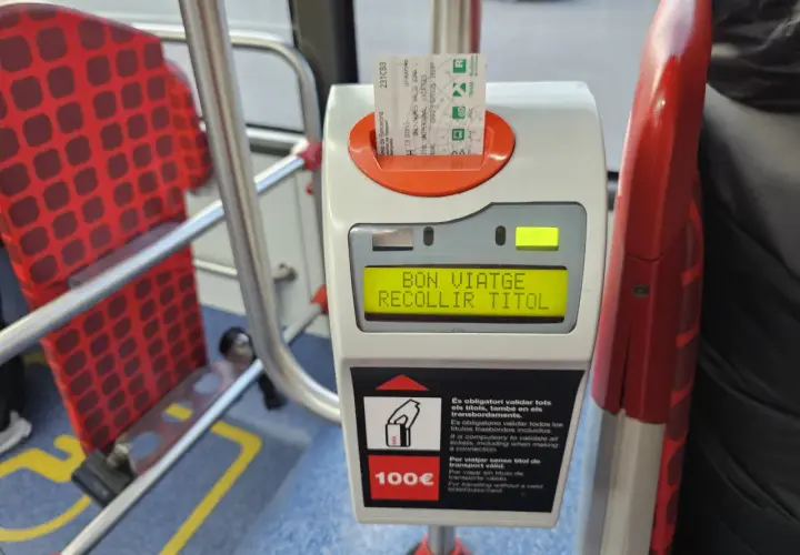 Validando billete para prendre le bus a Barcelone. Asientos rojos con patrón de cuadros en el interior del autobús.