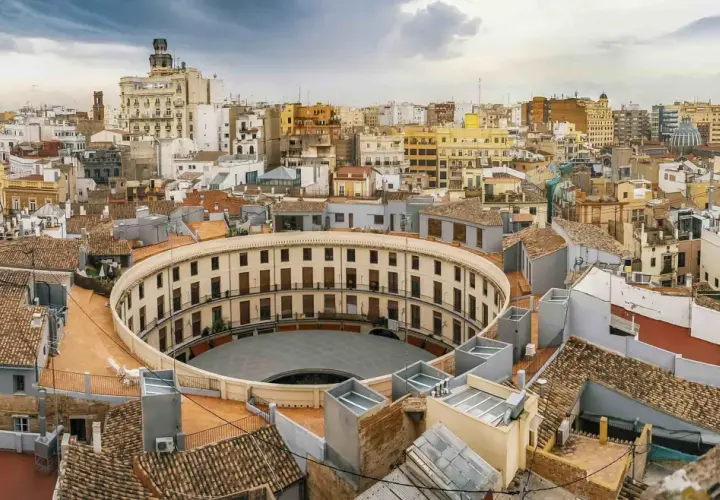 Vista aérea de la Plaza de Toros de Valencia, un edificio circular con balcones, como si se viajara en el tren de Barcelona a Valencia.