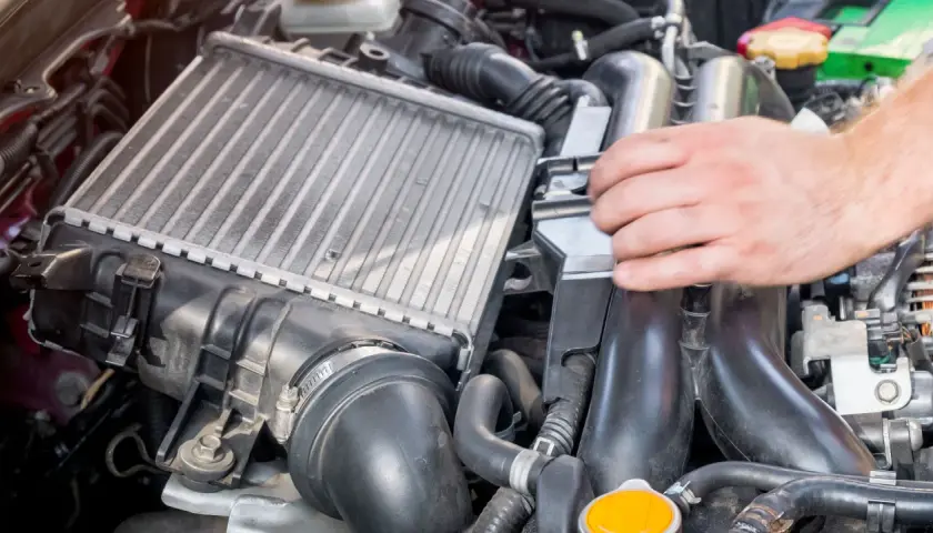 Mano ajustando un intercooler, componente clave para enfriar el aire del motor.