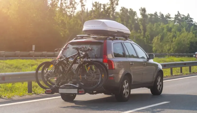 Turismo con portabicicletas y cofre de techo. La carga sobresale bastante, ideal para viajes largos.