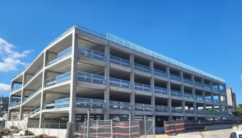Estructura de hormigón de un parking disuasorio en Barcelona, con varias plantas y barandillas metálicas, bajo un cielo azul.