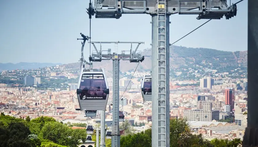 El teleférico de Montjuïc ofrece vistas panorámicas de Barcelona. Varias cabinas se deslizan sobre la ciudad, conectando puntos clave.