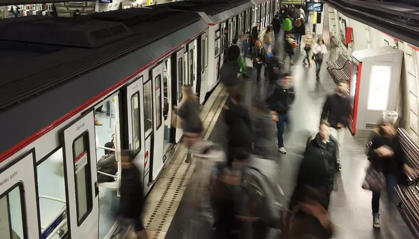 Gente abordando un tren en una estación de metro, con el movimiento borroso sugiriendo la actividad constante de las obras del metro de Barcelona.
