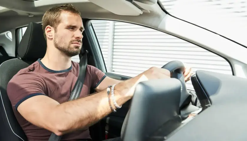 Hombre frustrado al volante, su coche no arranca.