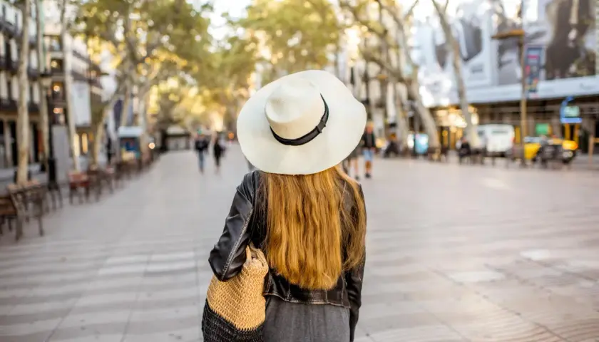 Mujer con sombrero pasea por Las Ramblas de Barcelona, un mapa visual de la ciudad.