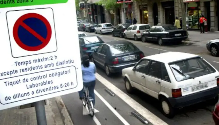 Zona verte Barcelona domingo: señal de estacionamiento, ciclista y coches aparcados en la calle.