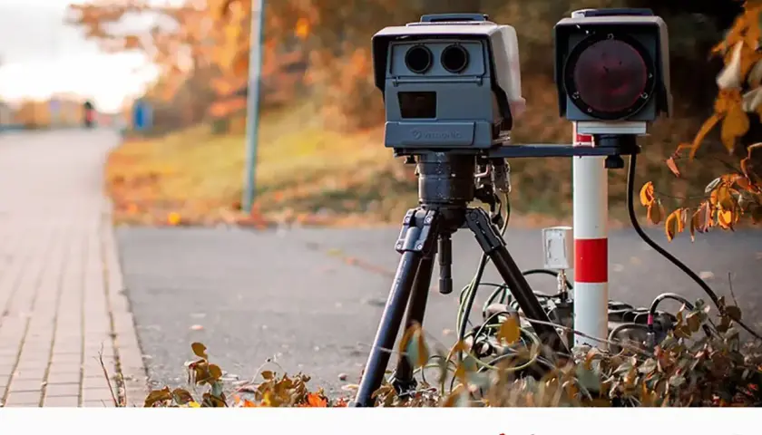 Un radar móvil, con su trípode y cámara, vigila la carretera en otoño. Así es como funciona un radar móvil.