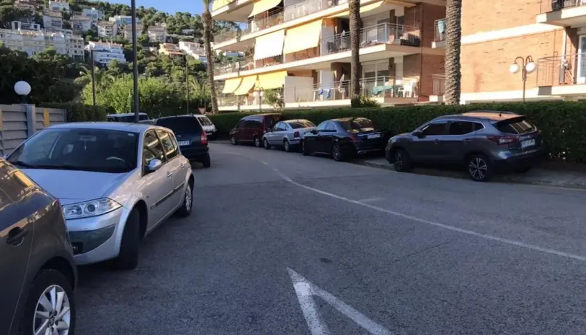 Coches aparcados en una calle con edificios residenciales al fondo. Hay varias opciones de parking gratuit Sitges.