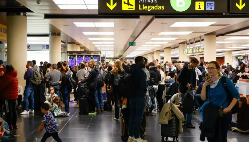 Gente esperando en un aeropuerto, buscando información sobre cómo usar el metro de Barcelona.